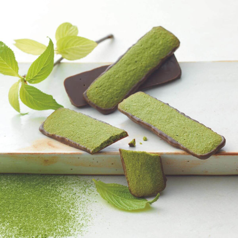 ROYCE' Chocolate - Baton Cookies Matcha (25 Pcs) - Image shows green cookies coated with brown chocolate on a white plate with green tea powder and some leaves for props.