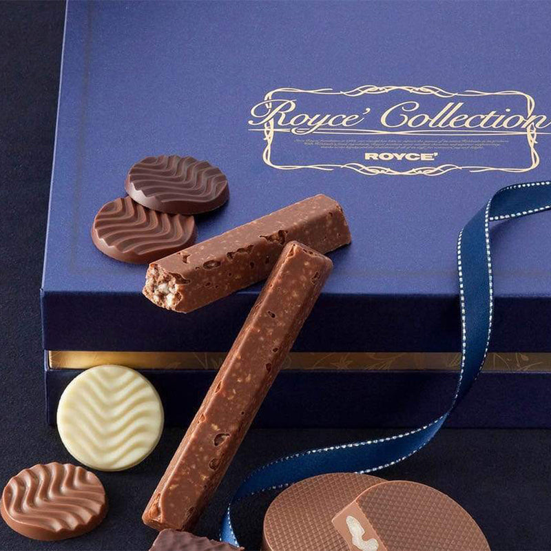 ROYCE' Chocolate - ROYCE' Collection Blue - Image shows a blue box. Gold text says ROYCE' Collection ROYCE'. Below the box are a mix of confections in various shapes and colors, with a blue ribbon accent.